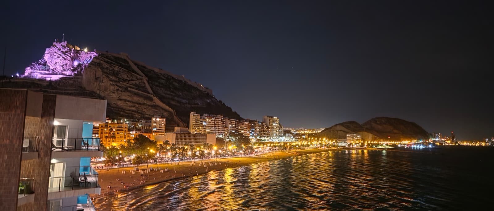 Vista nocturna de la playa y el castillo iluminado